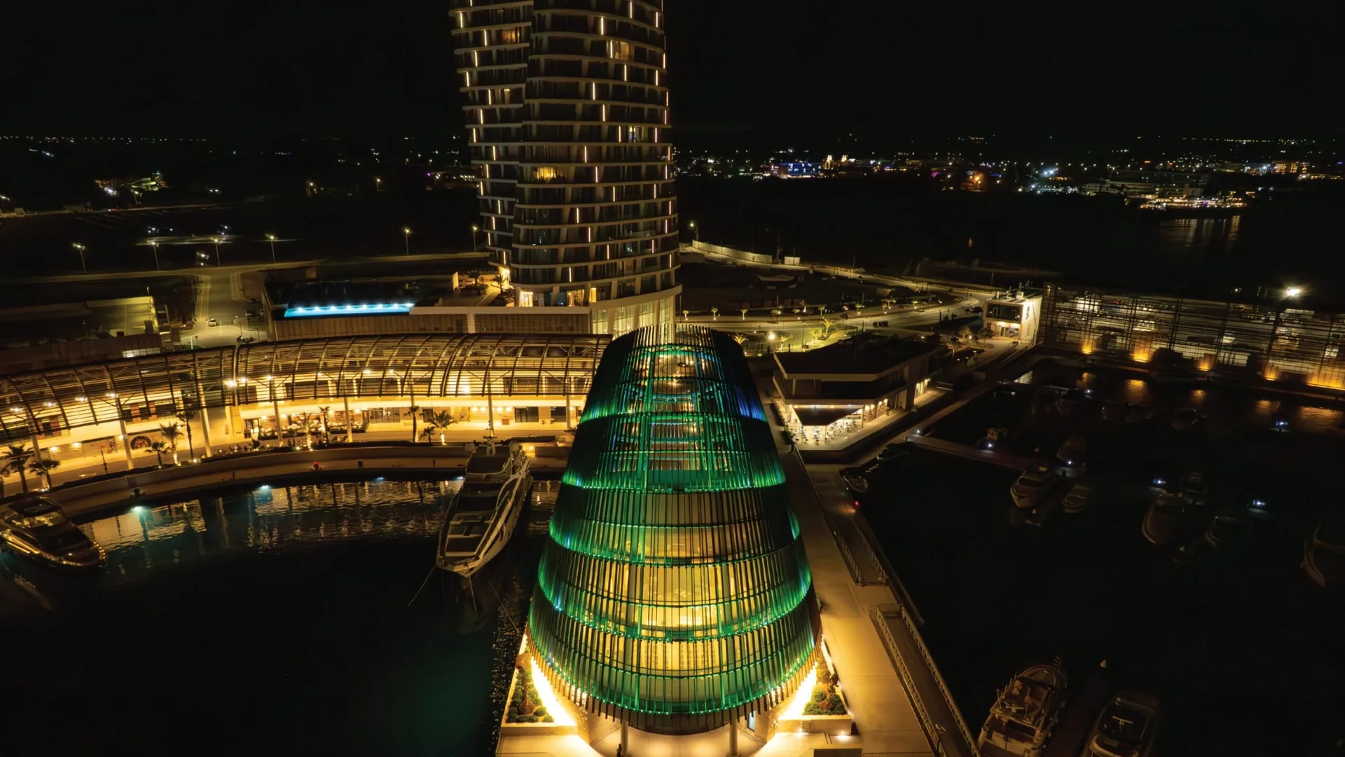 Illuminated modern wedding venue at Ayia Napa Marina in Cyprus at night, featuring contemporary architecture, luxury yachts, and a waterfront marina setting.