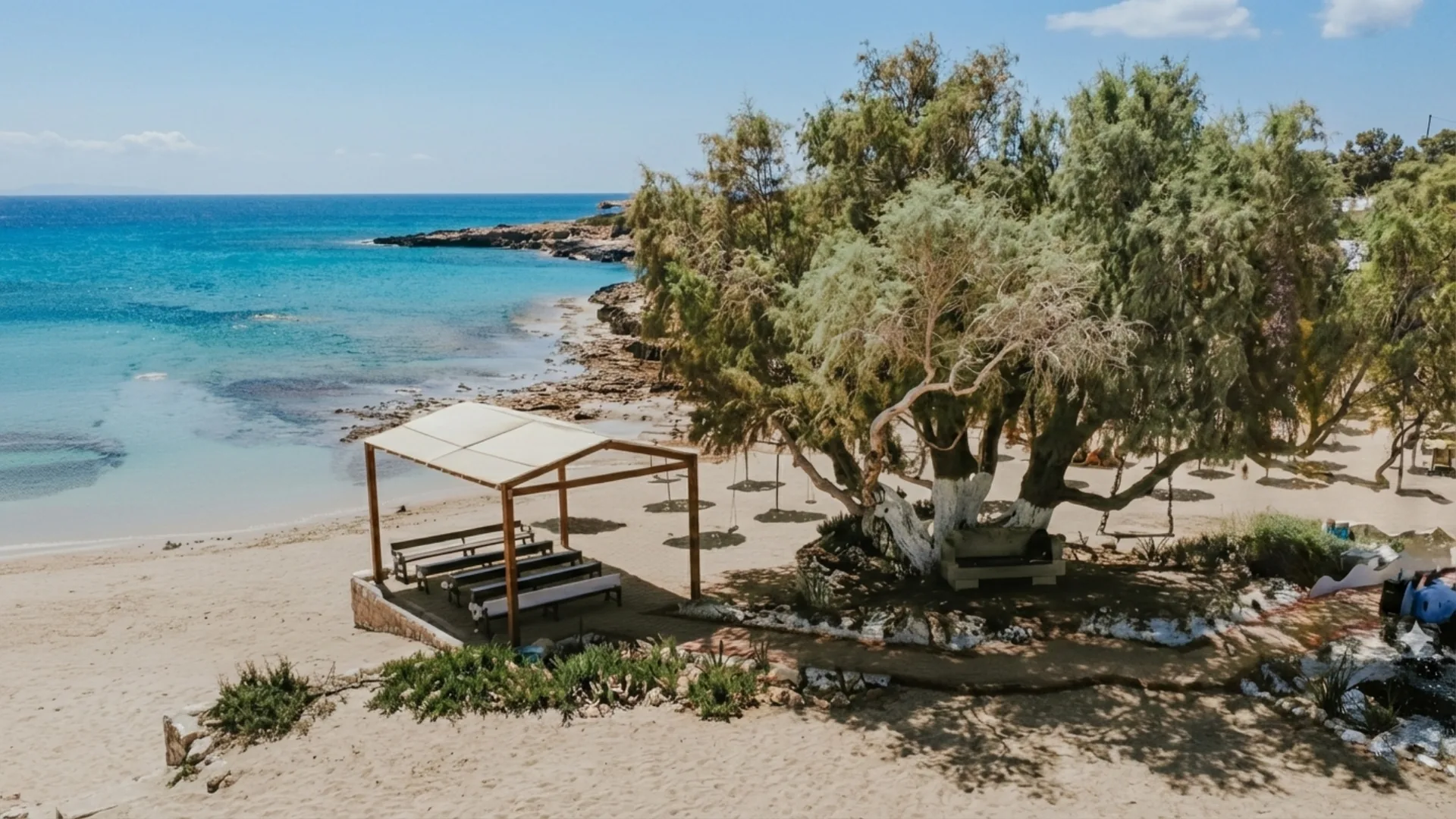 Ammos Kambouri beach wedding ceremony setup with wooden pergola and benches on the sand, overlooking turquoise Mediterranean waters in Cyprus