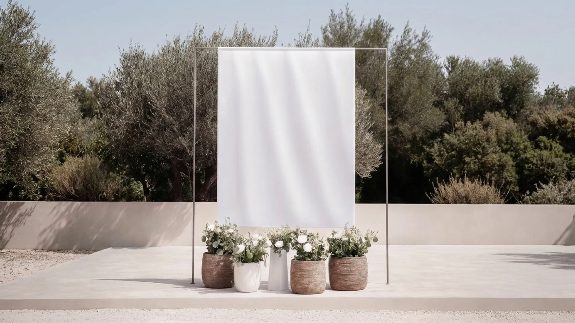 Minimalist outdoor wedding ceremony setup with white fabric backdrop, olive trees, and natural floral arrangements in a Mediterranean olive grove by Soomore.